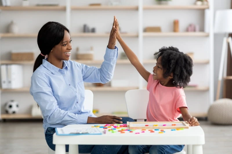 Young child practicing communication skills during an ABA therapy session with therapist using positive reinforcement